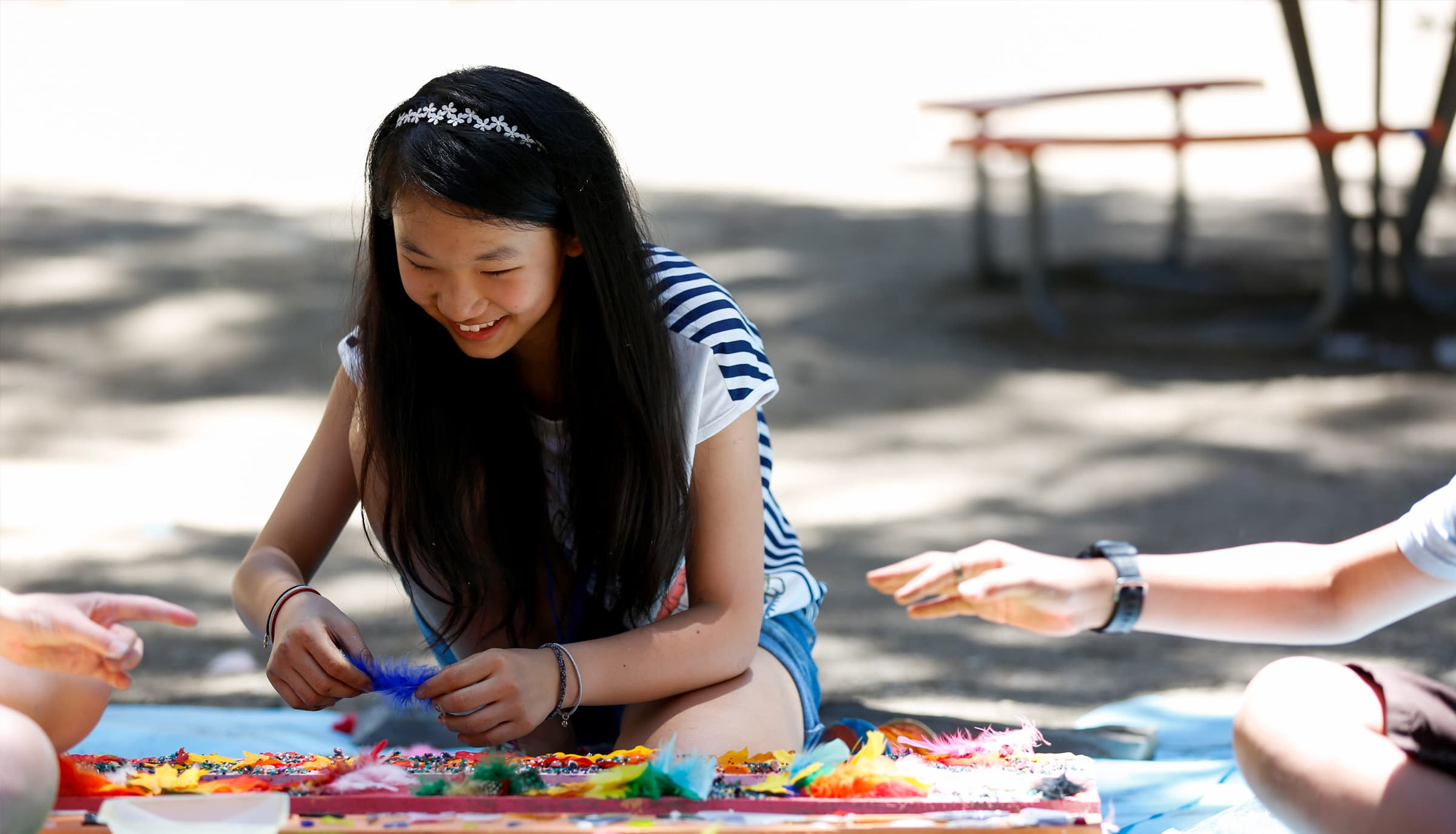 girl doing crafts on the ground outside with friends